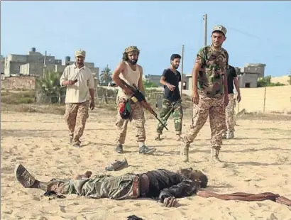  ?? STRINGER / REUTERS ?? Milicianos libios pasan junto al cadáver de un combatient­e del EI, a las afueras de Sirte
