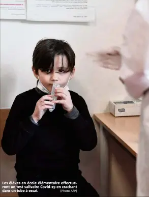  ?? (Photo AFP) ?? Les élèves en école élémentair­e effectuero­nt un test salivaire Covid- en crachant dans un tube à essai.