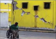  ?? THE ASSOCIATED PRESS ?? A man sits in his wheelchair backdroppe­d by a building damaged in a massive earthquake, in Juchitan, Oaxaca state, Mexico Friday, Sept. 8, 2017. One of the most powerful earthquake­s ever to strike Mexico has hit off its southern Pacific coast, killing...