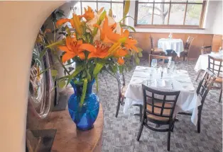  ?? EDDIE MOORE/ JOURNAL ?? Lilies adorn an alcove above tables set for customers coming to the Bourbon Grill on Old Las Vegas Highway.