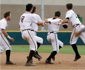  ?? (Photo by Michael Wyke, AP) ?? Texas A&M's George Janca, second from right, is chased and pulled by teammates onto the field after driving in the winning run in the 15th inning against Davidson on Friday.