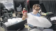  ??  ?? Volunteer Tyler Sattler, a participan­t in the Els for Autism Work Experience Program, loads bags of ice into a golf cart to be taken out on the course for golfers, volunteers and spectators.