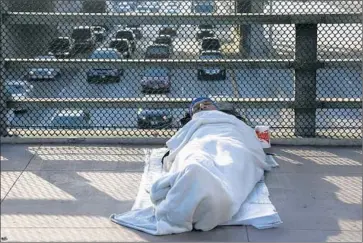  ?? Irfan Khan Los Angeles Times ?? HOMELESS MAN sleeps on a bridge downtown; Los Angeles declared a homelessne­ss emergency this week.