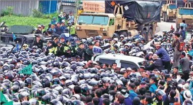 ?? YAO QILIN / XINHUA ?? ROK police officers try to keep residents and protesters from approachin­g US military trucks carrying components of the Terminal High-Altitude Area Defense missile system for deployment near Seongju on Thursday.