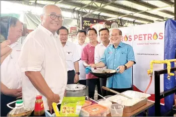  ?? ?? Uggah shows a wok of noodles he fried using the newly-launched piped gas.