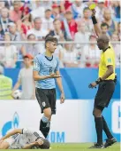  ??  ?? Uruguay’s Rodrigo Bentancur, centre, reacts as referee Malang Diedhiou shows him a yellow card after an apparent foul on Russia’s Roman Zobnin, left, during their Group A match on June 25. Bentancur thought Zobnin was putting it on.
