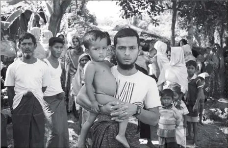  ??  ?? Rohingya refugee Mohammad Ayaz stands with his son Mohammad Osman, the two survivors from his family, on Thursday at an unregister­ed refugee camp in Ukhiya in southern Cox’s Bazar district, Bangladesh.