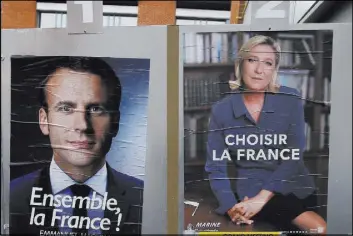  ?? Francois Mori The Associated Press ?? Campaign posters for French presidenti­al candidates Emmanuel Macron and Marine Le Pen hang in front of the polling station in Henin Beaumont, France, where Le Pen will vote in the runoff election Sunday.