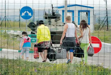  ?? DMITRY LOVETSKY/ THE ASSOCIATED PRESS ?? Ukrainians carry their belongings as they walk to cross the border into Russia at a crossing in eastern Ukraine, on Thursday.