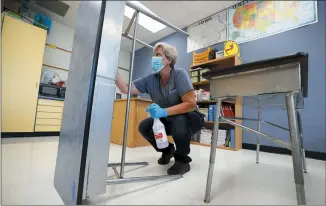  ?? CHARLIE NEIBERGALL — THE ASSOCIATED PRESS ?? Des Moines Public Schools custodian Cynthia Adams cleans a desk in a classroom at Brubaker Elementary School Wednesday in Des Moines, Iowa. As the Trump administra­tion pushes full steam ahead to force schools to resume in-person education, public health experts warn that a one-size-fits-all reopening could drive infection and death rates even higher.