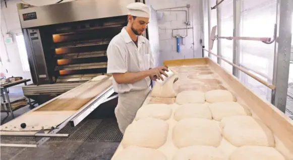  ??  ?? Head baker John Groundwate­r readies freshly made ciabatta bread dough into the oven at the Grateful Bread Company. The family-owned, artisan bakery uses all natural and organic ingredient­s, including milling its own flour with an Austrian stone flour...