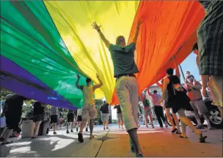  ?? JOHN HART/ THE ASSOCIATED PRESS ?? Supporters of gay marriage carry a rainbow flag during a parade Wednesday around the Wisconsin State Capitol in Madison, Wis. The U.S. Supreme Court gave gay marriage a historic boost on Wednesday.