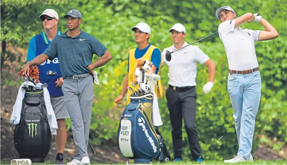  ?? Picture: Getty Images. ?? Justin Thomas plays his tee shot on the eighth hole watched by Tiger Woods and Rory McIlroy.