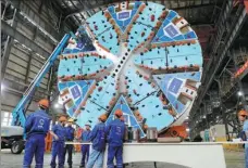  ?? FANG ZHE / XINHUA ?? Workers talk near a tunnel boring machine at Shanghai Tunnel Engineerin­g Ltd on Thursday. China’s GDP growth in the first three quarters turned positive at 0.7 percent year-on-year, according to the National Bureau of Statistics.