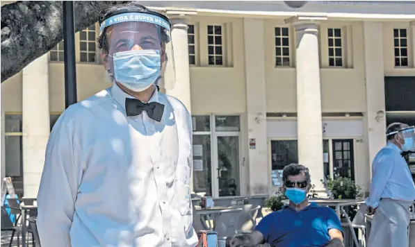  ??  ?? Staff and customers at the Deck beer garden in Estoril, near Lisbon, wear protective masks as more businesses reopen in Portugal’s emergence from Covid-19 lockdown