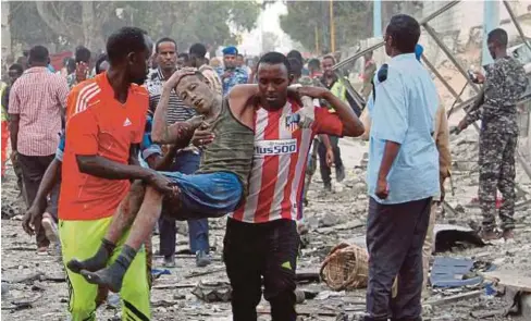  ??  ?? SEORANG lelaki yang cedera dibantu orang ramai selepas serangan bom di Hotel Naso Hablod Two di Mogadishu kelmarin. - Reuters