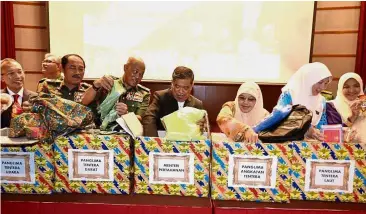  ??  ?? Festive cheer: Mohamad (centre) and other armed forces personnel preparing Hari Raya goodie bags for soldiers on duty at the Defence Ministry headquarte­rs in Kuala Lumpur.