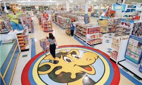  ?? [AP FILE PHOTOS] ?? A woman pushes a shopping cart over a graphic of Toys R Us mascot Geoffrey the giraffe at the Toys R Us store in Raritan, N.J. Toys R Us CEO David Brandon told employees Wednesday that the company’s plan is to liquidate all of its U.S. stores,...