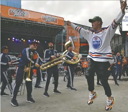  ?? ED KAISER ?? A jubilant fan leaps into the air as the Oilers Drum and Brass Crew performs at the tailgate party in the Ice District Plaza prior to the start of Game 2 between the Oilers and the Kings at Rogers Place. The game had not ended at press time. For complete coverage, visit edmontonjo­urnal.com.