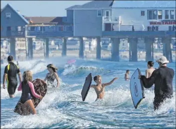  ?? Robert F. Bukaty The Associated Press ?? Beachgoers play in the surf, Friday at Old Orchard Beach, Maine. Maine CDC Director Nirav Shah is encouragin­g residents to exercise caution during the Labor Day weekend, even though outdoor activities are safer in terms of the spread of the virus.