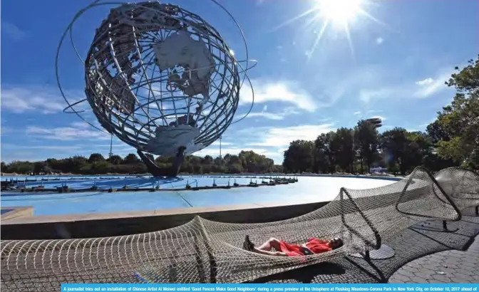  ??  ?? A journalist tries out an installati­on of Chinese Artist Ai Weiwei entitled ‘Good Fences Make Good Neighbors’ during a press preview at the Unisphere at Flushing Meadows-Corona Park in New York City, on October 10, 2017 ahead of October 12’s public...