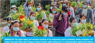  ?? — AFP ?? MANDALAY: This photo taken and received courtesy of an anonymous source yesterday shows protesters carrying A-taui pots filled with Thingyan festival flowers while taking part in a demonstrat­ion against the military coup in Mandalay.
