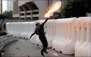  ?? AP/KIN CHEUNG ?? An anti-government protester throws a Molotov cocktail during a demonstrat­ion Sunday near the Central Government Complex in Hong Kong.