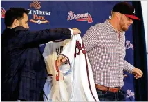  ?? CURTIS COMPTON / CCOMPTON@AJC.COM ?? Braves GM Alex Anthopoulo­s helps left-handed reliever Will Smith, who was signed as a free agent in the offseason, with his jersey in November. Anthopoulo­s has built one of MLB’s deepest bullpens.