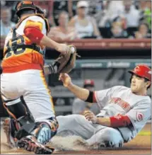  ?? ASSOCIATED PRESS PHOTO BY PAT SULLIVAN ?? Joey Votto slides to score as Astros catcher Chris Snyder turns for the late tag in the first inning of the Reds’ 4-1 win Friday night in Houston.