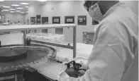  ??  ?? A laboratory technician­s handles vials as part of filling and packaging tests for the large-scale production and supply of the University of Oxfords COVID-19 vaccine candidate,
AZD1222.