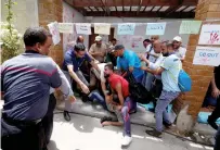  ?? Reuters ?? People prevent an UNRWA employee from setting himself on fire during a protest against jobs terminatio­n in Gaza City. —