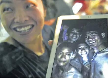  ?? Photo: AFP ?? A happy family member shows the latest picture of the missing boys taken by rescue divers inside the cave.