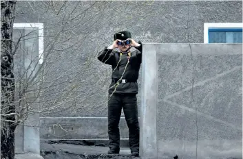  ?? JOHANNES EISELE/GETTY IMAGES ?? A North Korean soldier uses his binoculars to look across the Yalu river near Sinuiju, opposite the Chinese border city of Dandong, on Friday. China’s Foreign Minister Wang Yi is calling for dialogue to ease tensions between North Korea and the U.S.