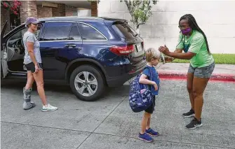  ??  ?? Beverly Okosun, right, program director, takes the temperatur­e of Luke Koudelka, 6, as his stepmother, Sierra, drops him off Tuesday at the Quillan Center.