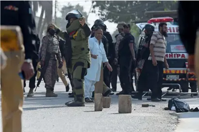  ?? AFP ?? A bomb disposal squad member warns onlookers before checking a bag belonging to an attacker outside the Chinese consulate after the attack in Karachi on Friday. —