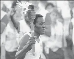  ?? PETER LEABO/AP ?? Rafer Johnson carries the Olympic torch through Los Angeles Memorial Coliseum in 1984.