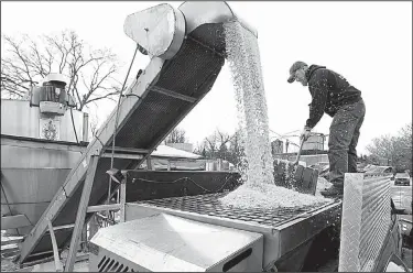  ?? AP/The Winchester Star/JEFF TAYLOR ?? Tim Ritter, of Winchester, Va., uses a snow shovel to guide 4,000 pounds of salt being loaded into his spreader truck while preparing for the first measurable snowfall of the season Thursday.