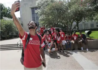  ?? Elizabeth Conley / Houston Chronicle ?? Karim Motani, a junior at UH, takes a group photo of incoming students during an orientatio­n on campus. A decline in internatio­nal applicatio­ns at the university follows three years of growth.