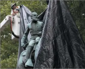  ?? AP PHOTO/STEVE HELBER ?? City workers drop a tarp over the statue of Confederat­e General Stonewall Jackson in Justice park in Chrlottesv­ille, Va., Wednesday, Aug. 23, 2017. The move to cover the statues is intended to symbolize the city’s mourning for Heather Heyer, killed...