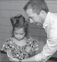  ??  ?? Tracy Finn of Fayettevil­le shows his daughter Elizabeth how to hold a small red-eared slider turtle. The turtles were part of a display from the Arkansas Game and Fish Commission.