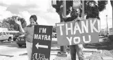  ?? STEPHEN HUDAK/ORLANDO SENTINEL ?? Mayra Uribe, holding the “I’M MAYRA” sign, and her husband, Kevin Sutton, with the “THANK YOU” sign, waved to motorists at the corner of Michigan Street and Orange Avenue on Wednesday.