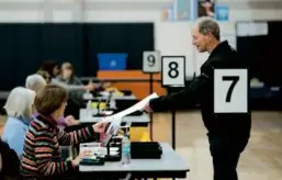  ?? JONATHAN WIGGS /GLOBE STAFF ?? In Franklin on Super Tuesday, Steve Swanson picked up his ballot to vote in the primary election at the high school. State officials expected lower turnout this year.