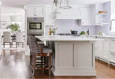  ?? ?? After a floor-to-ceiling support column was removed from the island, the eye can focus on other things, like marble countertop­s, a Fisher & Paykel cooktop and a geometric, three-dimensiona­l backsplash.