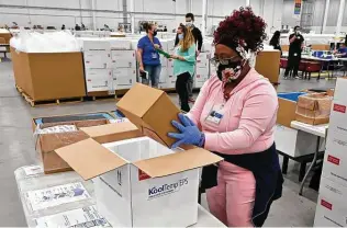  ?? Timothy D. Easley / Associated Press ?? An employee with the Mckesson Corp. packs a box of the Johnson and Johnson COVID-19 vaccine into a cooler for shipping Monday from a facility in Shepherdsv­ille, Ky.