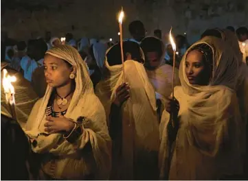  ?? AHMAD GHARABLI/GETTY-AFP ?? Ethiopian Orthodox Christian pilgrims hold candles Saturday during the “Holy Fire” ceremony at Holy Sepulchre Church in Jerusalem’s Old City on the eve of Orthodox Easter. In the annual ceremony, a flame taken from Jesus’ tomb is used to light believers’ candles. Israel’s strict limits on event capacity dimmed the tradition for a second year.