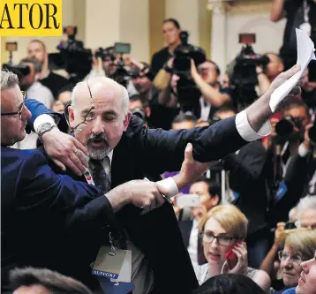  ?? ANTTI AIMO-KOIVISTO / LEHTIKUVA VIA THE ASSOCIATED PRESS ?? Security removes Sam Husseini, a journalist who held up a sign reading “Nuclear Weapon Ban Treaty,” before a press conference between U.S. President Donald Trump and Russian President Vladimir Putin in Helsinki on Monday.