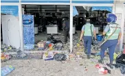  ??  ?? Dos policías ingresan a un supermerca­do saqueado.