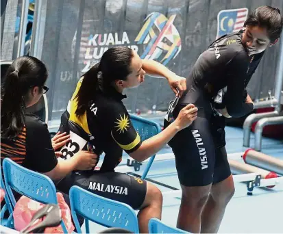  ??  ?? Wait a minute: Malaysian cyclist Fatehah Mustapa adjusting the number on Jupha Somnet’s jersey at the National Velodrome in Nilai.