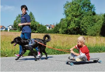  ?? Foto: Thorsten Jordan ?? Hundeführe­rin Tanja Birnbaum zeigt mit ihrem sechsjähri­gen Sohn Dominik wie Hund Mogli ein Longboard ziehen kann. Das lie ben auch die Kinder einer Familie aus Stoffen, die Birnbaum unterstütz­t.