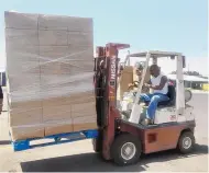  ??  ?? A volunteer hauls dozens of food boxes to distribute Wednesday in Las Cruces. The boxes contain two kinds of meat, sour cream, cheese, milk, fruits and vegetables purchased from farms and ranches by the government.